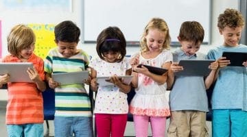 Smiling schoolchildren using digital tablet
